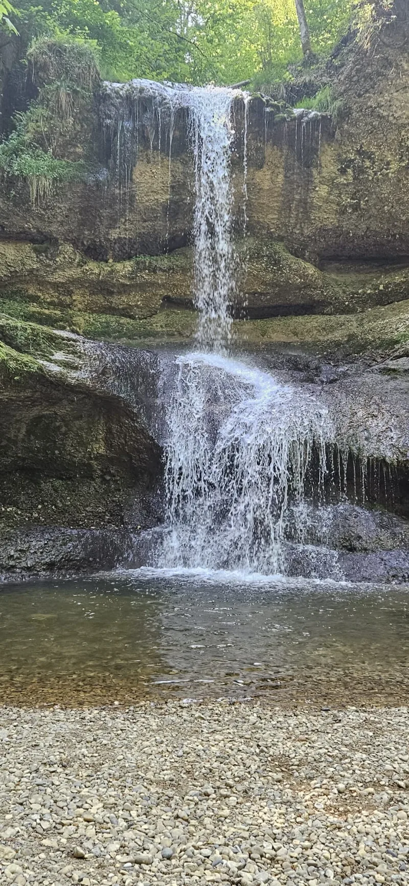 Wasserfall zwischen Felsen und grünem Wald